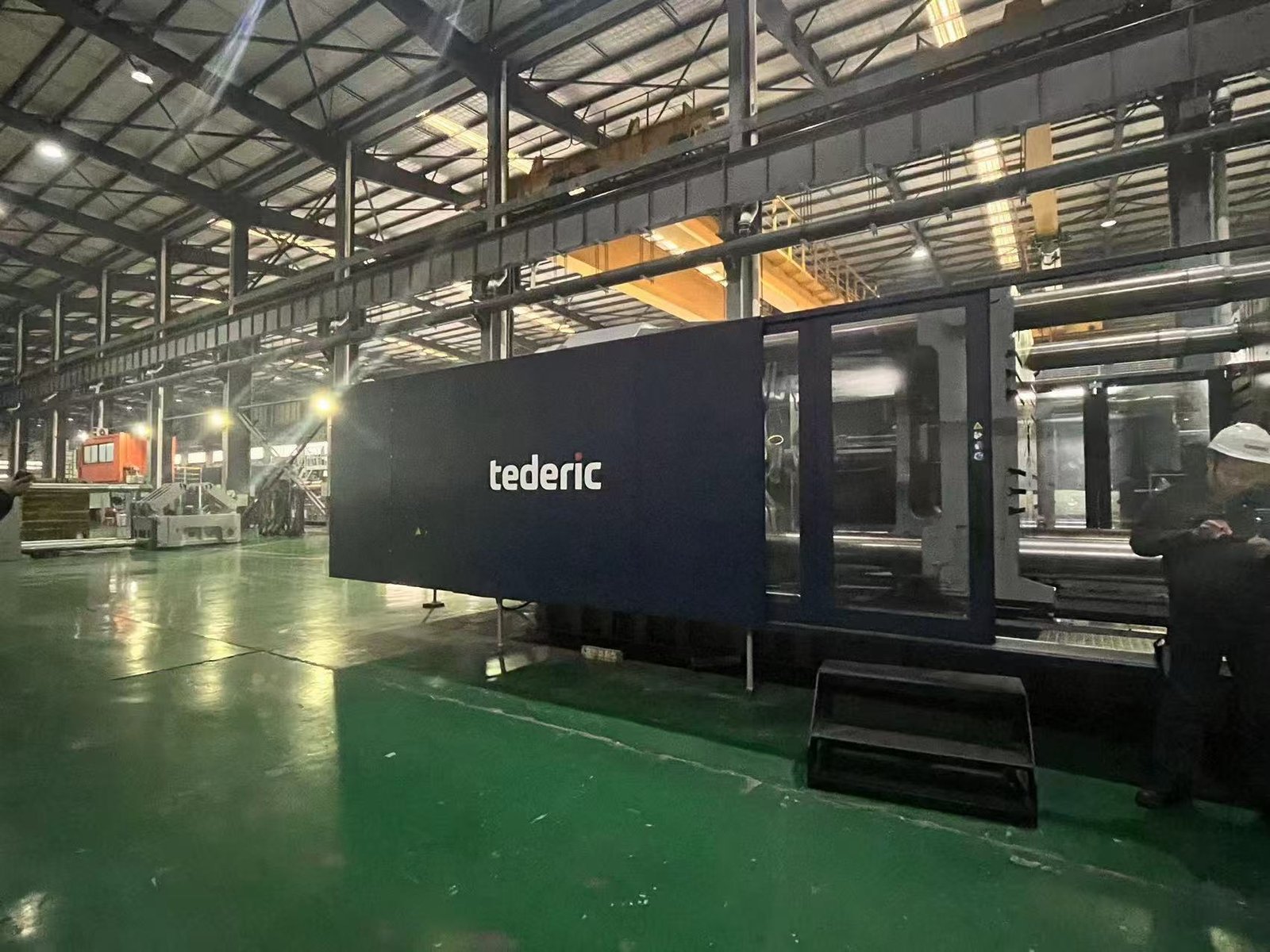 An industrial factory floor with several large injection molding machines